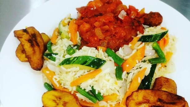 Un plato de comida con arroz, verduras y plátanos fritos.