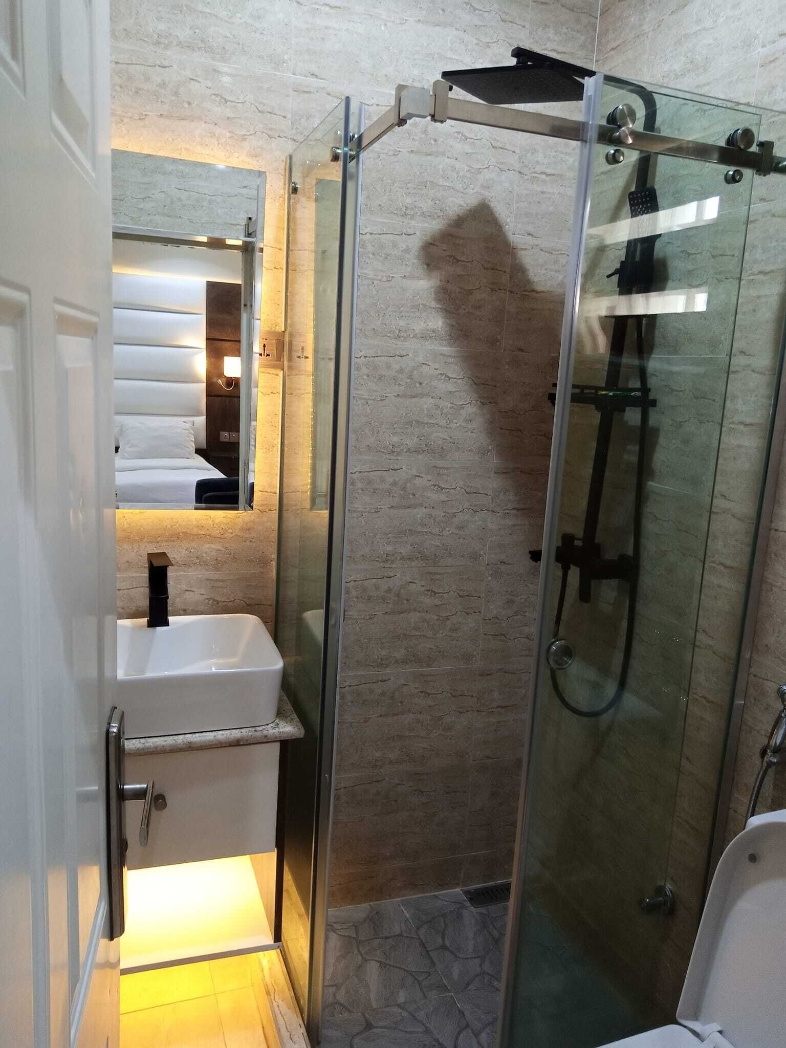 A modern bathroom with a glass-enclosed shower, a white sink, and a mirror above the sink.