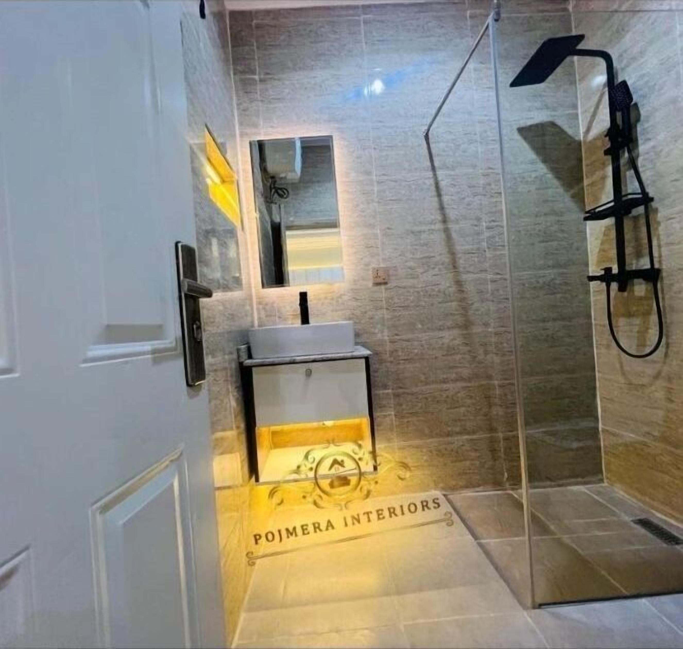 A modern bathroom with a glass shower enclosure, a white sink, and a mirror above it.