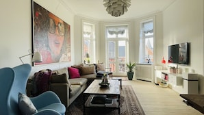 A living room with a large painting, a sofa, a coffee table, and a TV.