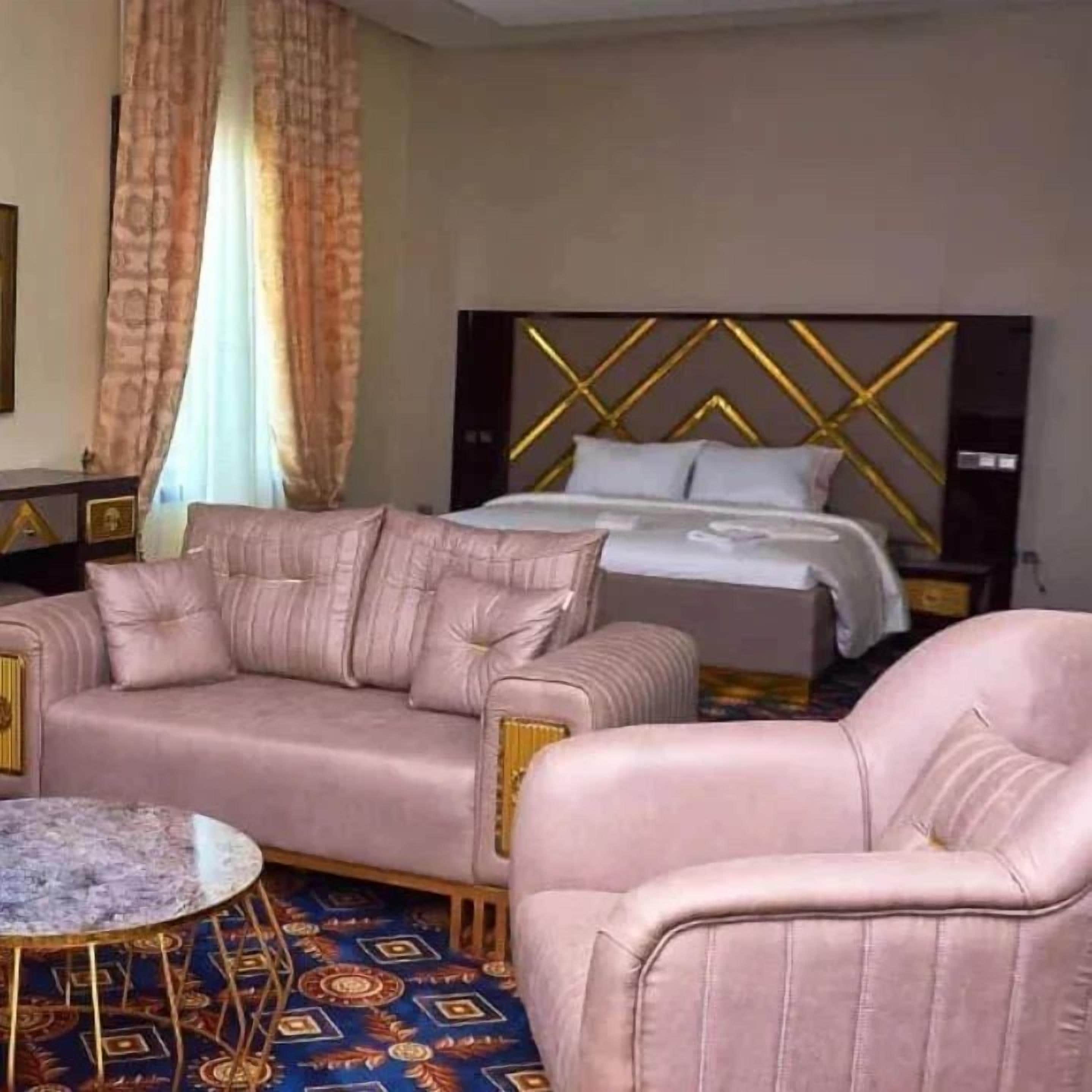 A hotel room with a bed, a sofa, a chair, and a small table.