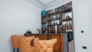 Angolo bar con un bancone in legno e due poltrone trapuntate.