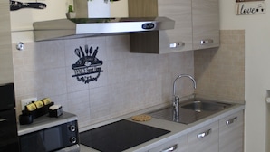 A modern kitchen with a microwave, sink, and cabinets. There is a plant on the countertop and a sign on the wall that says "eat x drink love".