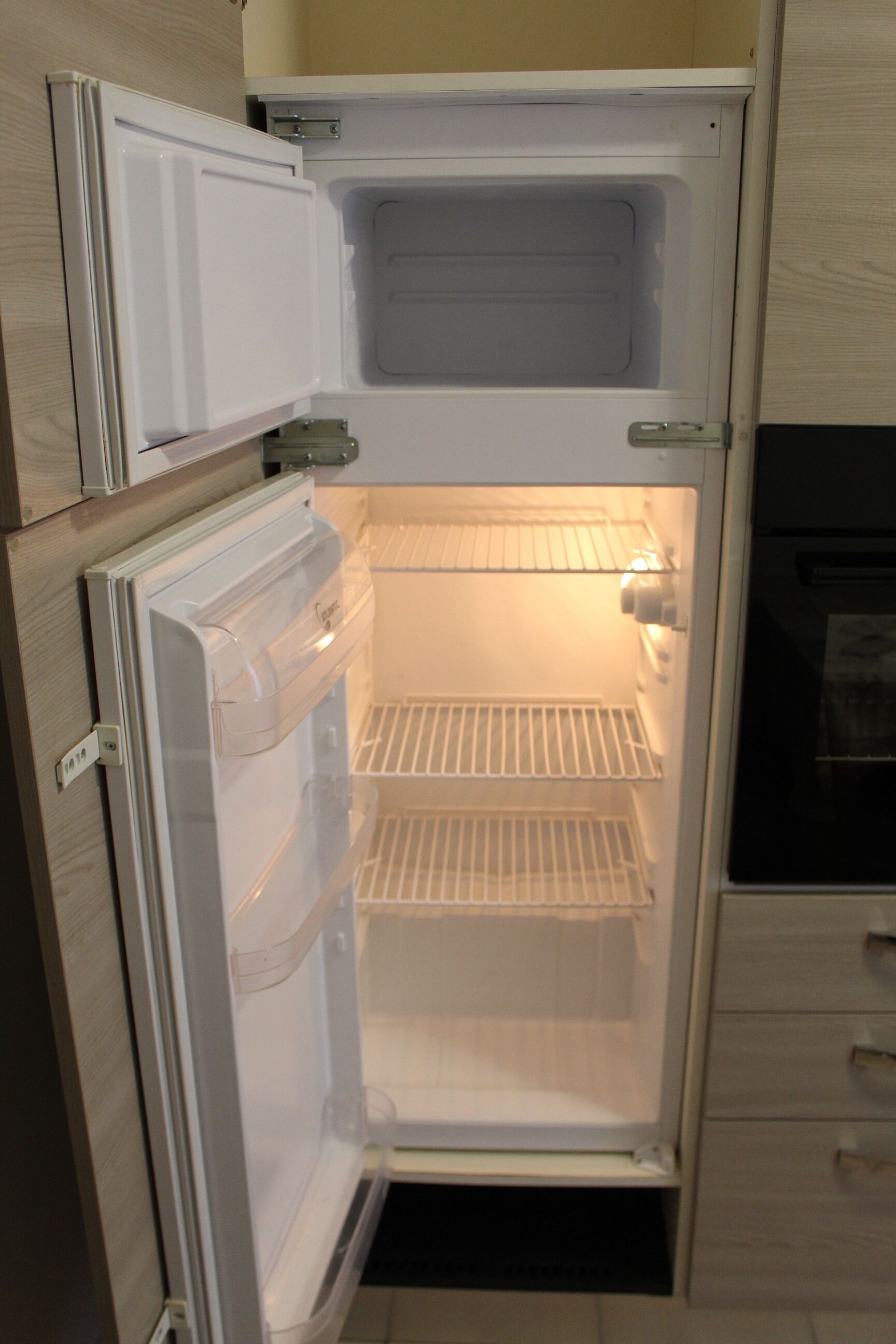 An open refrigerator with two shelves and a freezer compartment.