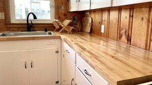 Una cucina con mobili in legno, un lavandino in acciaio inossidabile e una finestra che offre vista sugli edifici esterni.