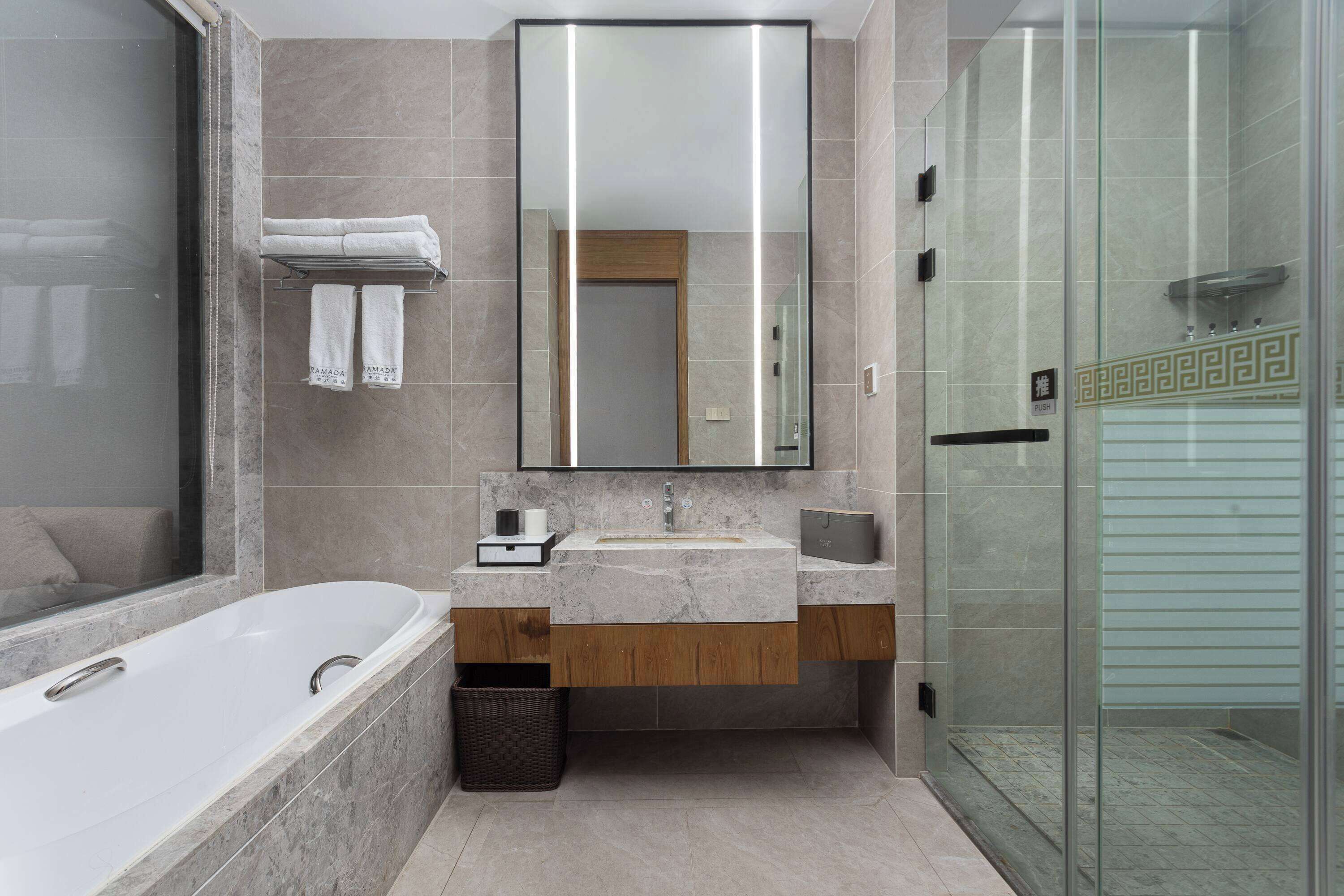 Un baño moderno con una bañera independiente, un espejo grande y un box de ducha de vidrio.