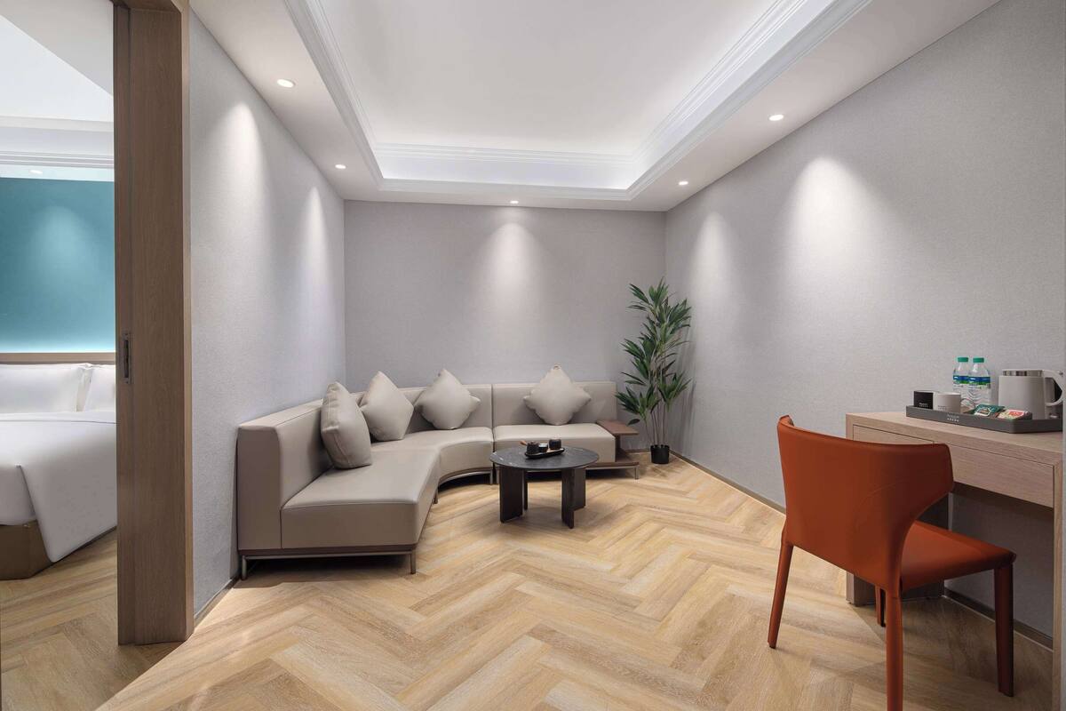 A modern living room with a sofa, coffee table, and a desk with a chair.