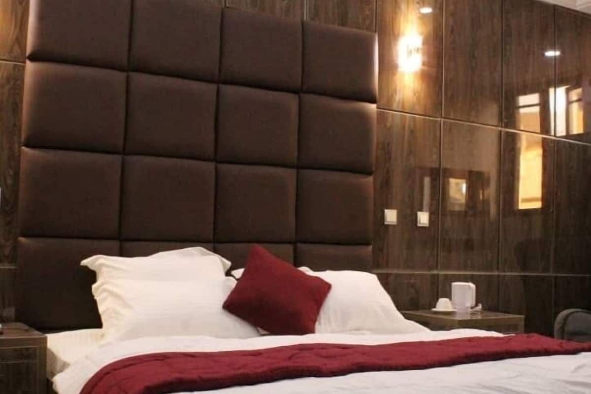 Une chambre à coucher avec un grand lit, des lambris en bois foncé sur les murs et une table de chevet avec une lampe.