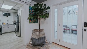 A modern kitchen with white cabinets, a stainless steel refrigerator, and a large window.
