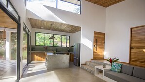 Una cocina moderna con una isla central, techo de madera y ventanas amplias.