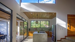 Una cocina moderna con una isla central, ventanas amplias y techo de madera.