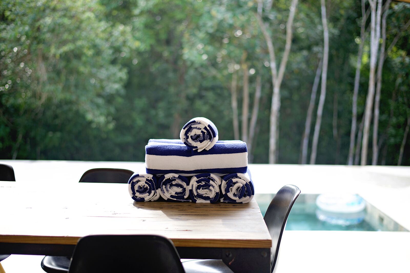 Una mesa de madera con una bandeja de estampado azul y blanco, frente a un denso bosque verde.