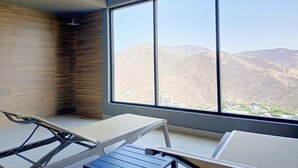 A room with a large window, a wooden wall, and a table with chairs. - Apartasuites Ambar Roca - Rodadero (Santa Marta)