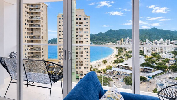 A balcony with a view of a beach and high-rise buildings. - Apartasuites Ambar Roca - Rodadero (Santa Marta)