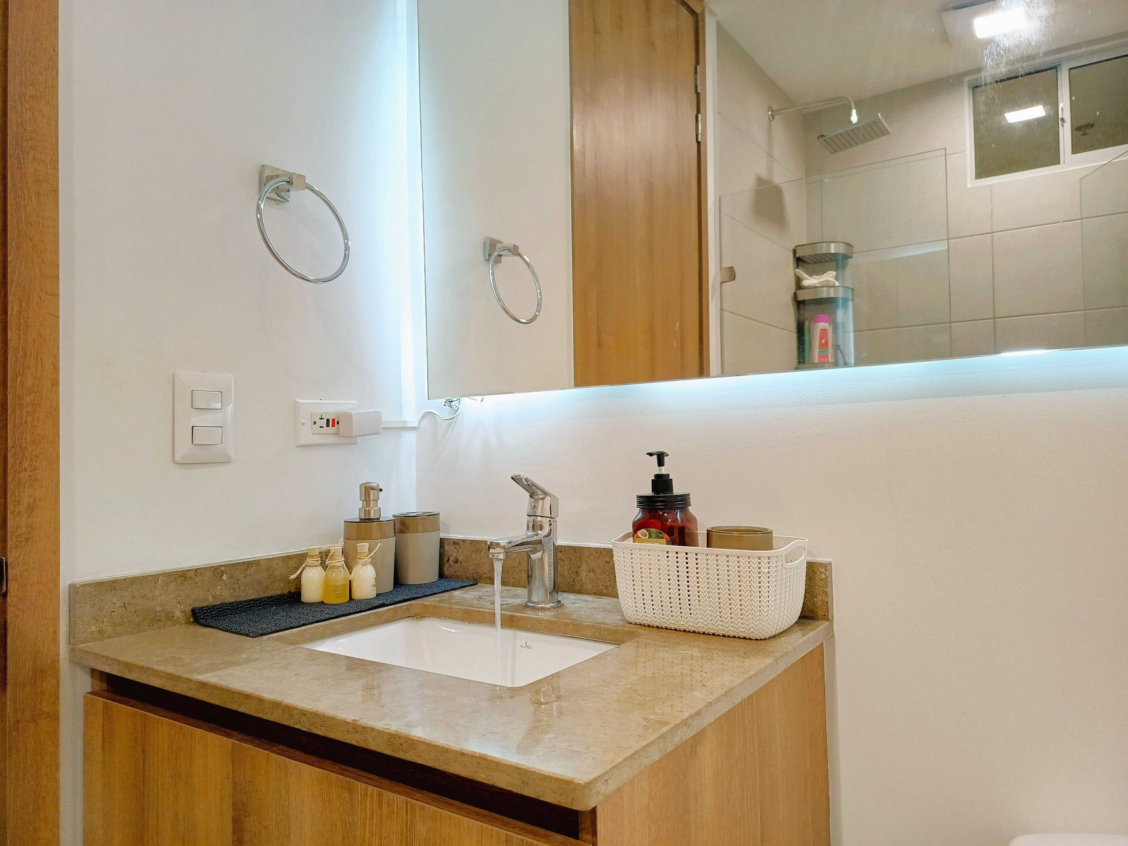 A bathroom with a sink, mirror, and toiletries.
