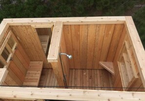 Una sauna de madera con un banco, una zona de ducha y una pequeña ventana.