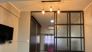A modern bedroom with a sliding door, a bed with a dark cover, a TV mounted on the wall, and a ceiling light fixture. - Cares Apartament, Castelar Centro, Buenos Aires. (Castelar)
