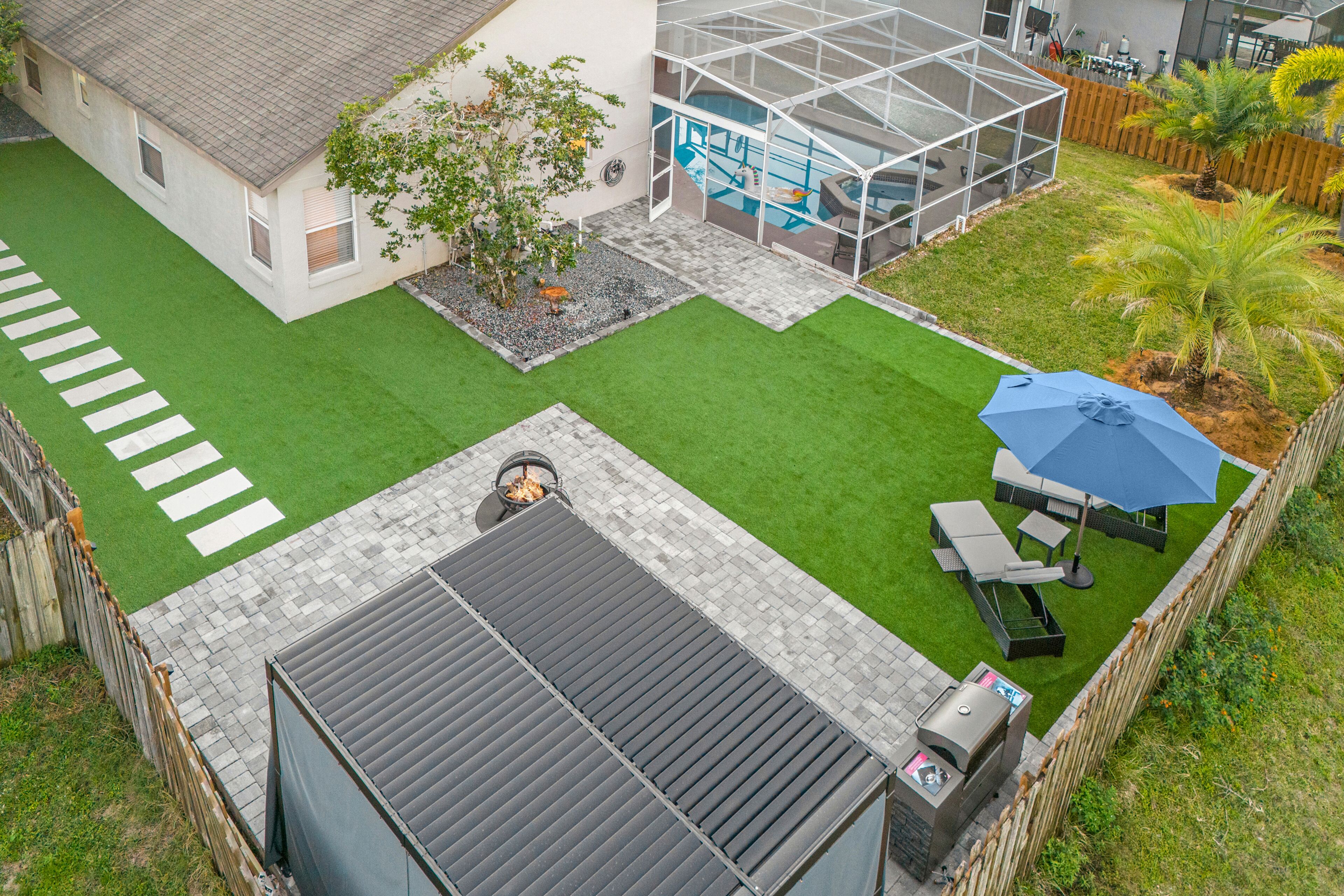 Un jardin à l’arrière d’une maison, avec une piscine, un patio couvert et un espace barbecue.