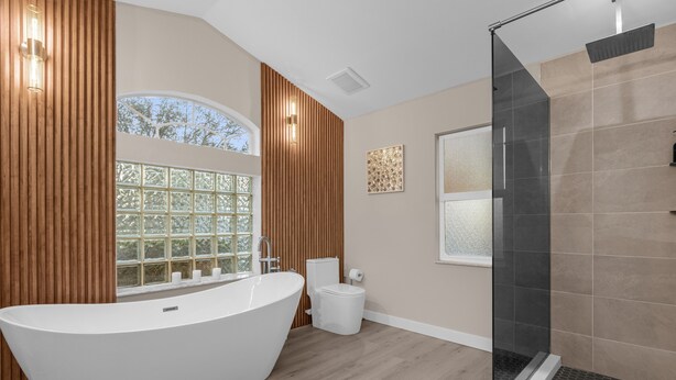 A modern bathroom with a freestanding bathtub, a glass-enclosed shower, and a window with a view of trees. - Luxury 4BD 3BA Free Heated Pool Villa/Fenced Backyard (Davenport)