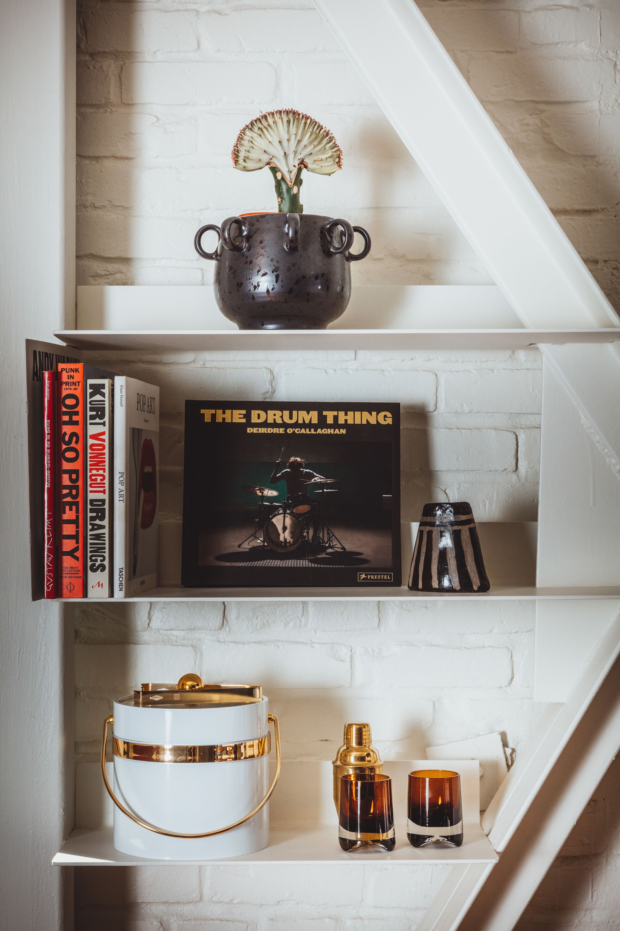 A bookshelf with books, a decorative vase, and a small sculpture.