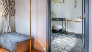 A bathroom with a herringbone-patterned tile wall, a wooden bench, a towel rack, and a mirror with a gold frame. - Gold-Diggers Hotel (Los Angeles)