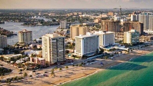 Vista aérea de una ciudad costera con hoteles de gran altura, una playa y un río.