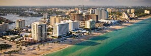 An aerial view of a coastal city with high-rise hotels, a beach, and a river.