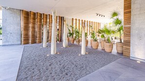 Ein moderner Innenraum mit Betonboden, Holzlamellen an den Wänden und mehreren großen Topfpflanzen.