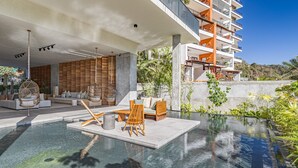Ein moderner Poolbereich im Freien mit Sitzgelegenheit und Blick auf ein mehrgeschossiges Gebäude.