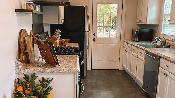 A kitchen with a central island, a refrigerator, a microwave, and a sink. - Charming Cottage Downtown Hattiesburg (Hattiesburg)