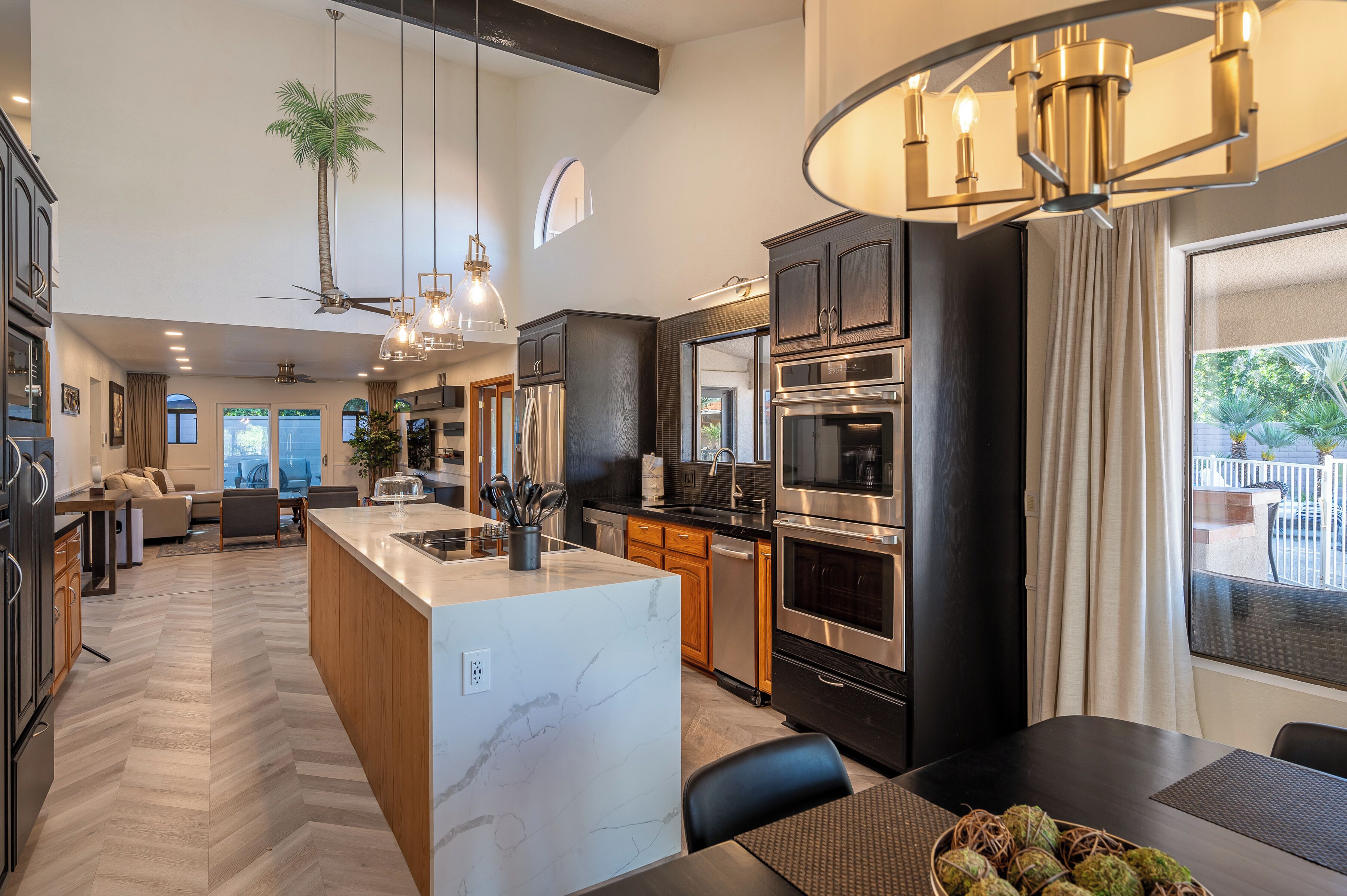 A modern kitchen with a central island, stainless steel appliances, and a dining area with a view.
