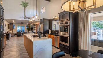 A modern kitchen with a central island, stainless steel appliances, and a dining area with a view.