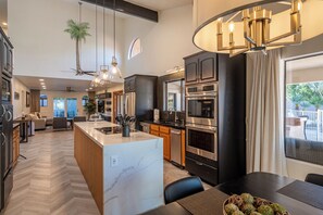 A modern kitchen with a central island, stainless steel appliances, and a dining area with a view.
