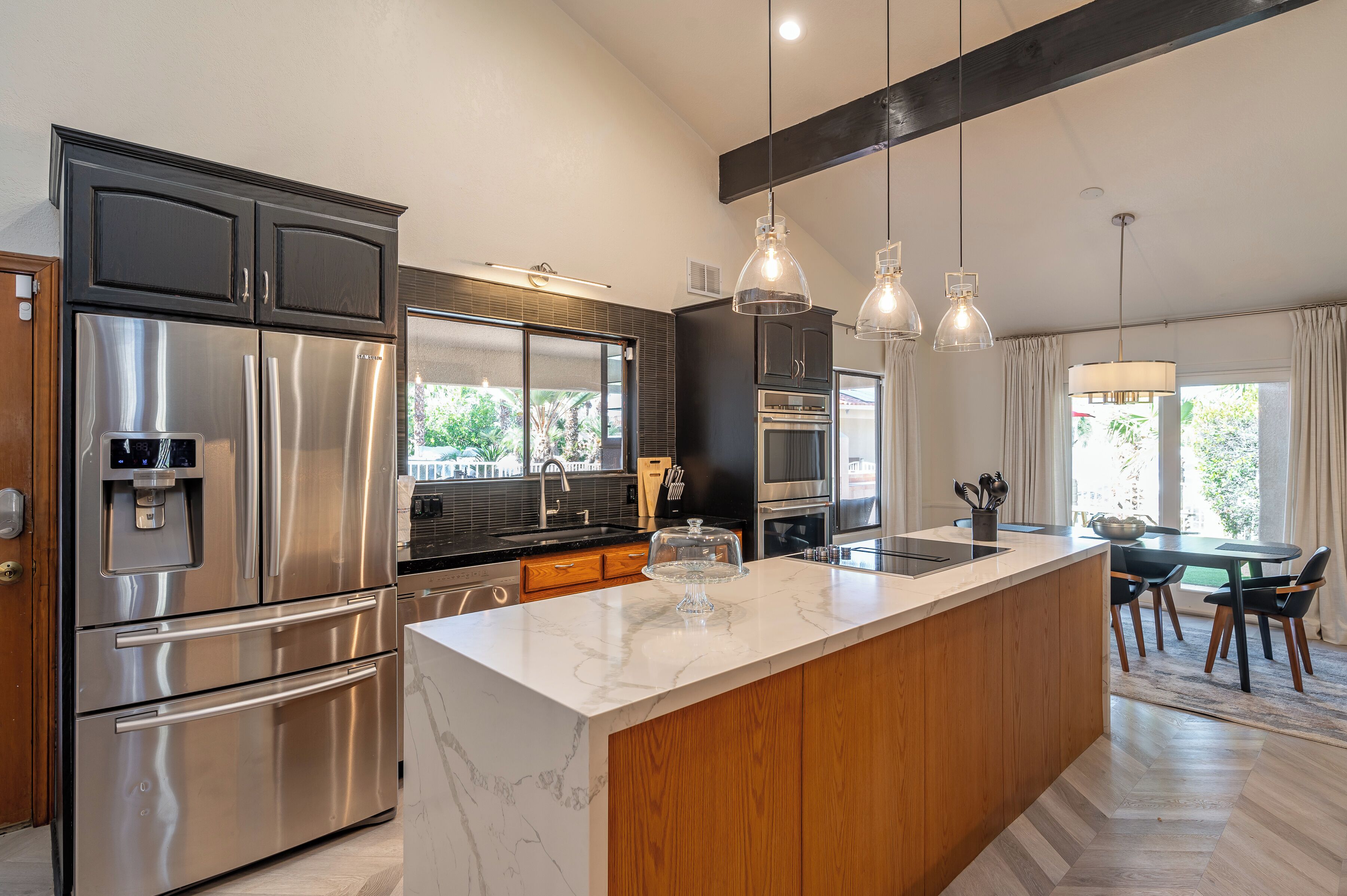 A modern kitchen with stainless steel appliances, a marble island, and pendant lighting.