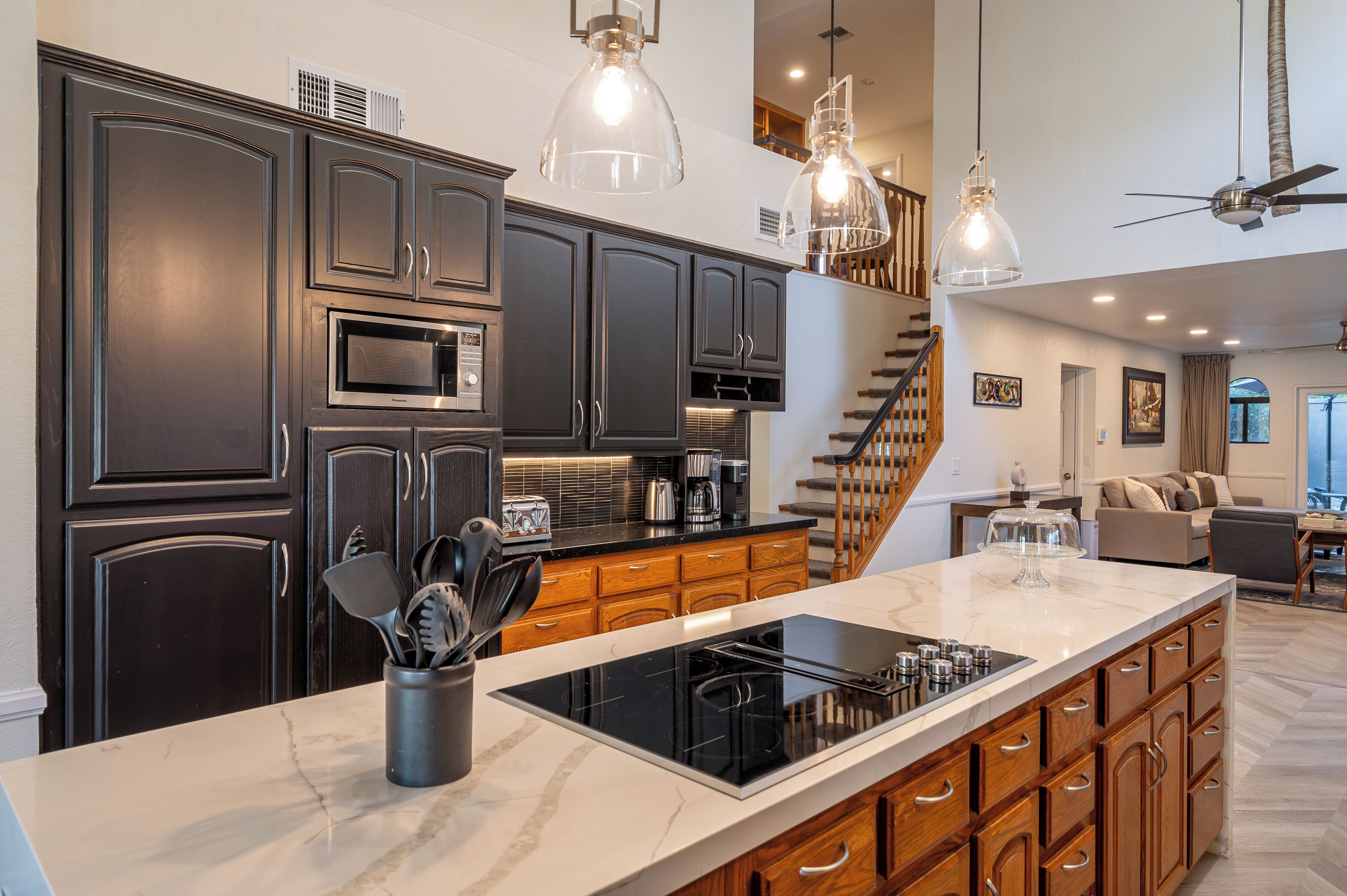 A modern kitchen with dark cabinetry, a large island, and a built-in microwave.
