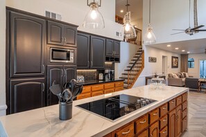 A modern kitchen with dark cabinetry, a large island, and a built-in microwave.