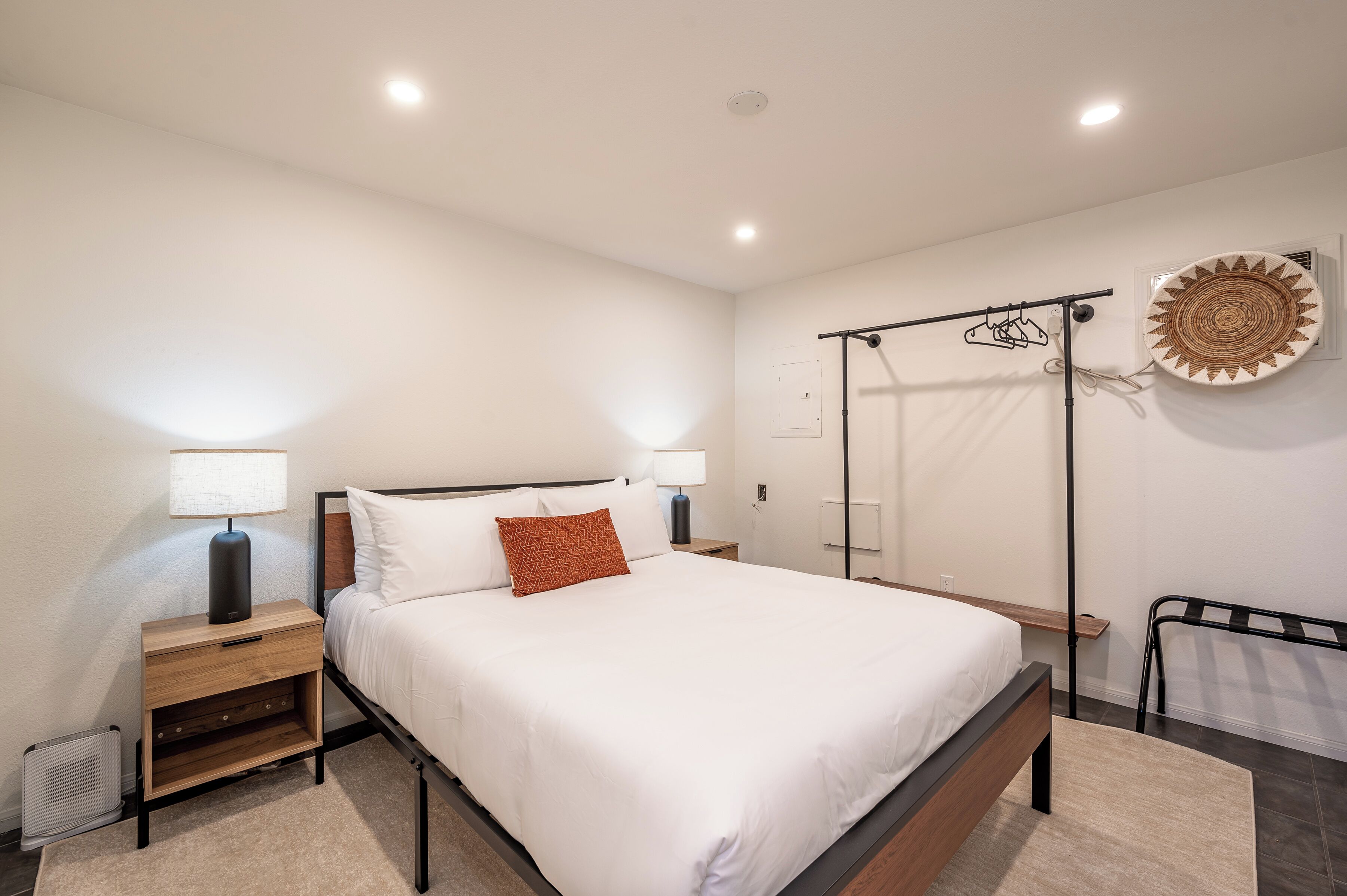 Una camera da letto moderna con un letto grande, comodini, un'asciugatrice a parete e una piastra decorativa a parete.