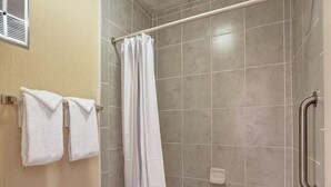 Une salle de bain avec une douche, des toilettes et deux serviettes suspendues à un porte-serviettes.