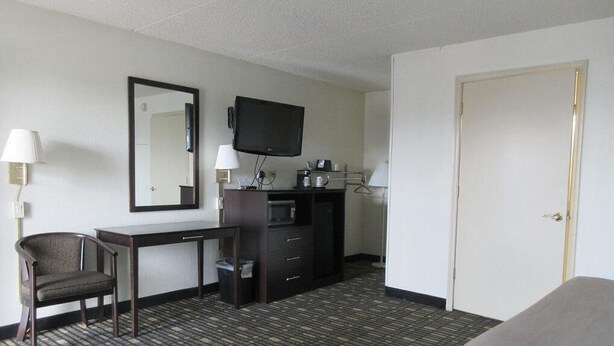 Une chambre d’hôtel équipée d’un bureau, d’une chaise, d’une télévision, d’une armoire et d’une porte.
