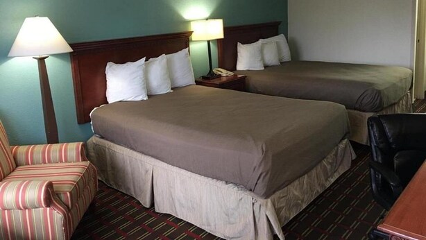 A hotel room with two beds, a striped armchair, a desk, and two bedside lamps. - Deluxe 2 Double Beds in Music Valley (Nashville)