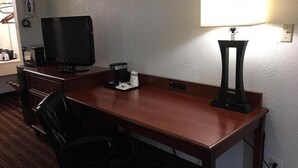 A hotel room with a wooden desk, a black office chair, a television, a lamp, and a coffee maker. - Deluxe 2 Double Beds in Music Valley (Nashville)
