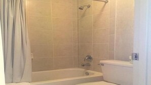 A bathroom with a bathtub, toilet, and shower curtain. - Deluxe 2 Double Beds in Music Valley (Nashville)