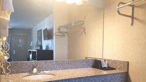 A bathroom with a granite countertop sink, a mirror, a towel rack, and a towel dispenser. - Deluxe 2 Double Beds in Music Valley (Nashville)