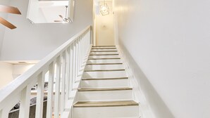 A staircase with white railings and wooden steps leading to a landing with a light fixture. - Updated Tallahassee Townhome: 3 Mi to Downtown! (Tallahassee)
