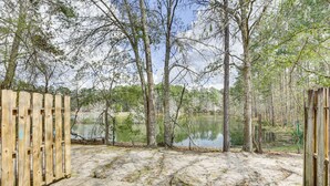 A concrete pathway leading to a wooden gate, surrounded by trees and a body of water. - Updated Tallahassee Townhome: 3 Mi to Downtown! (Tallahassee)