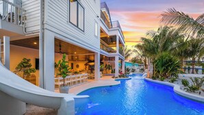 A modern resort with a swimming pool, outdoor seating, and a sunset view. - Lagoon Pool/Slide/Spa - Beach Volleyball/Ping Pong (Sarasota)