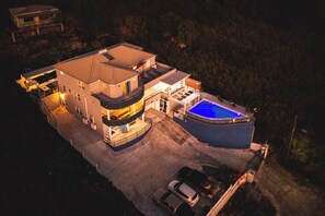 A modern two-story house with a swimming pool, a covered patio, and a garage.