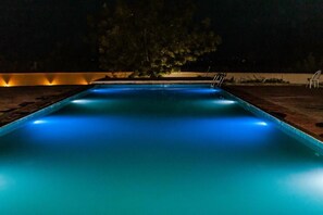 A swimming pool at night with blue lighting. - Grand Palazzo Hotel (Abuja)