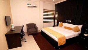 A hotel room with a bed, a desk, a chair, and a TV. - Grand Palazzo Hotel (Abuja)