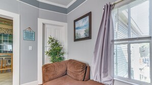 Ein Zimmer mit einem braunen Ledersofa, einem Fenster mit Jalousien, einer Tür, einem gerahmten Bild und einem Schild an der Wand.